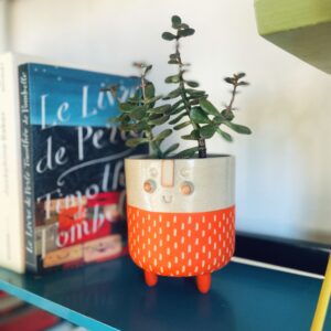 Pot en céramique, visage rieur, orange, sur un étagère vintage